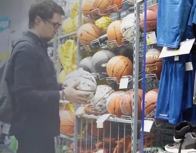 Cliente eligiendo un balón en el estante de una tienda deportiva