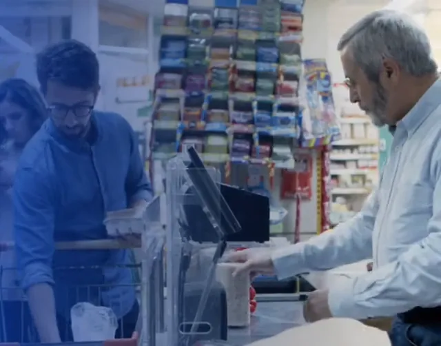 Cajero atendiendo a un cliente que paga en el mostrador de un negocio con punto de venta