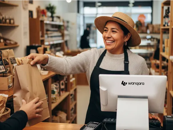 Comerciante entregando un producto en su local con el punto de venta Wanqara